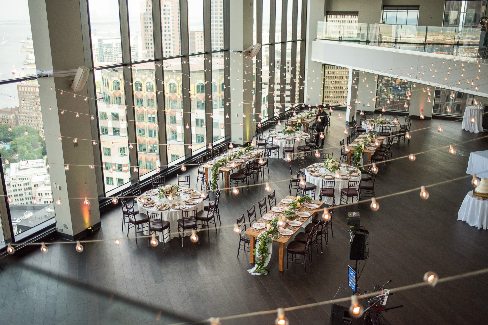 Setting up a wedding reception room at the State Room, a venue with long windows and cafe lights.