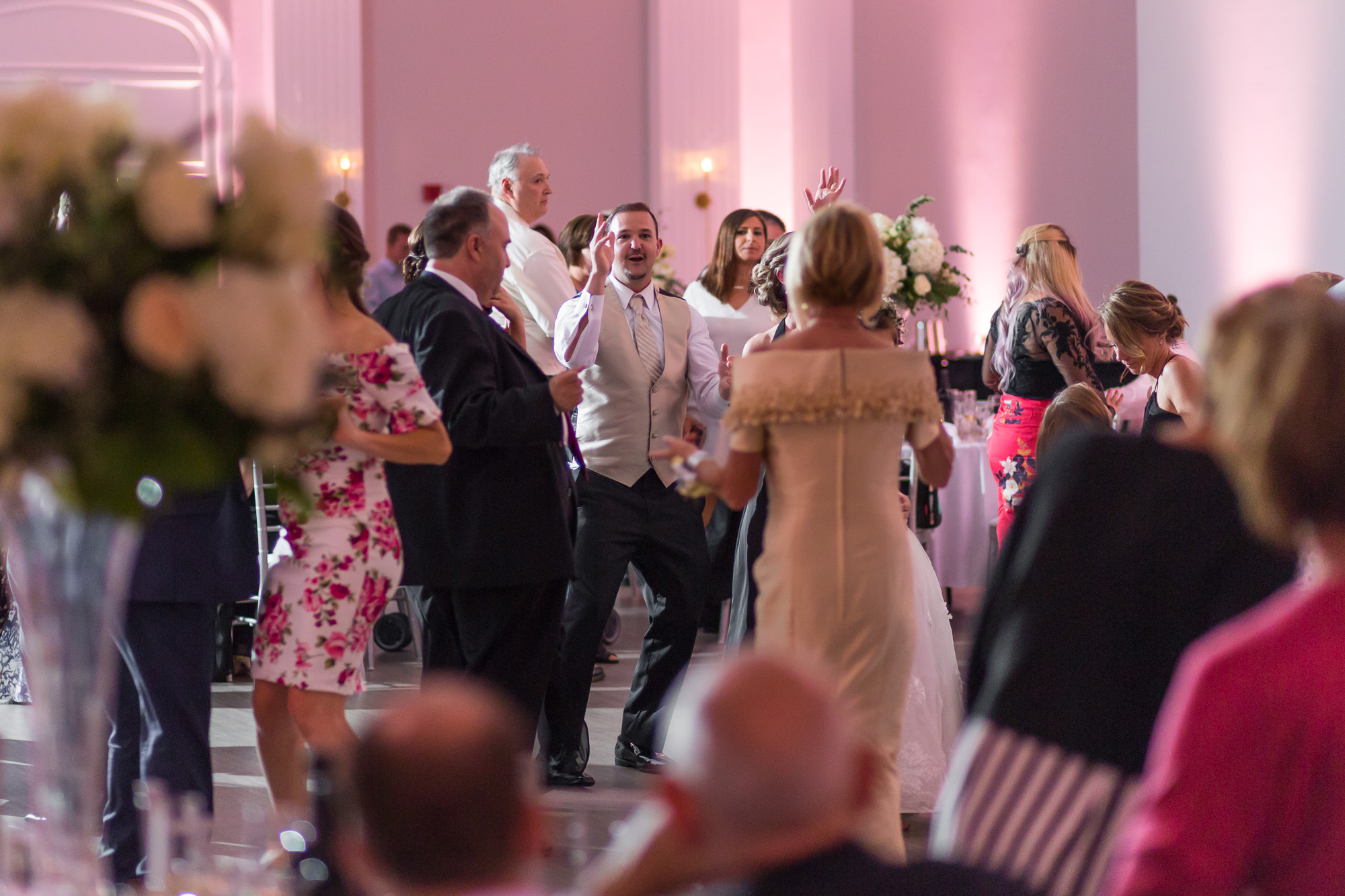 wedding guests dancing to DJ music in a Rhode Island reception ballroom with pink uplighting