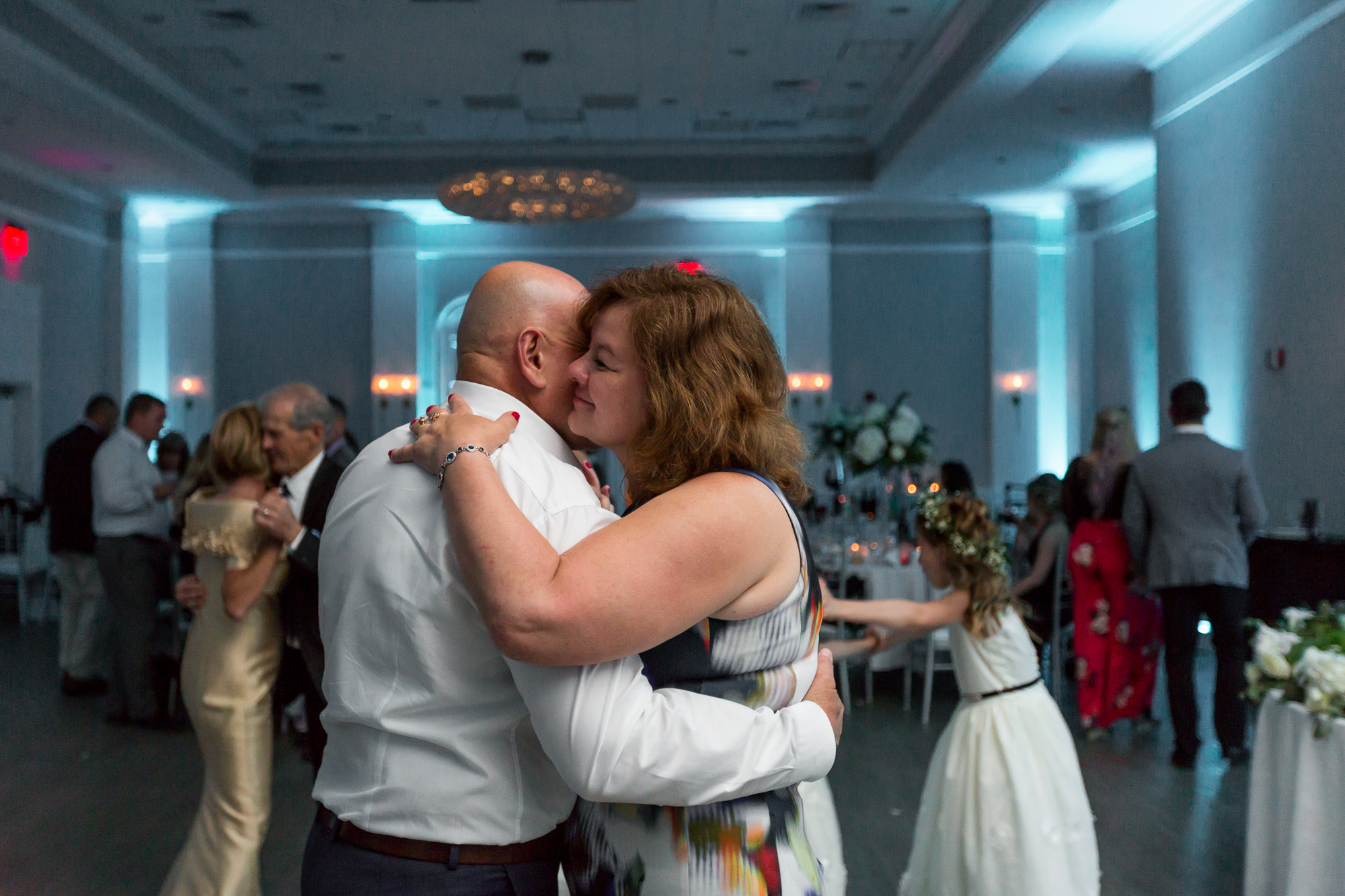 couple dancing to a wedding song in a room with blue uplighting